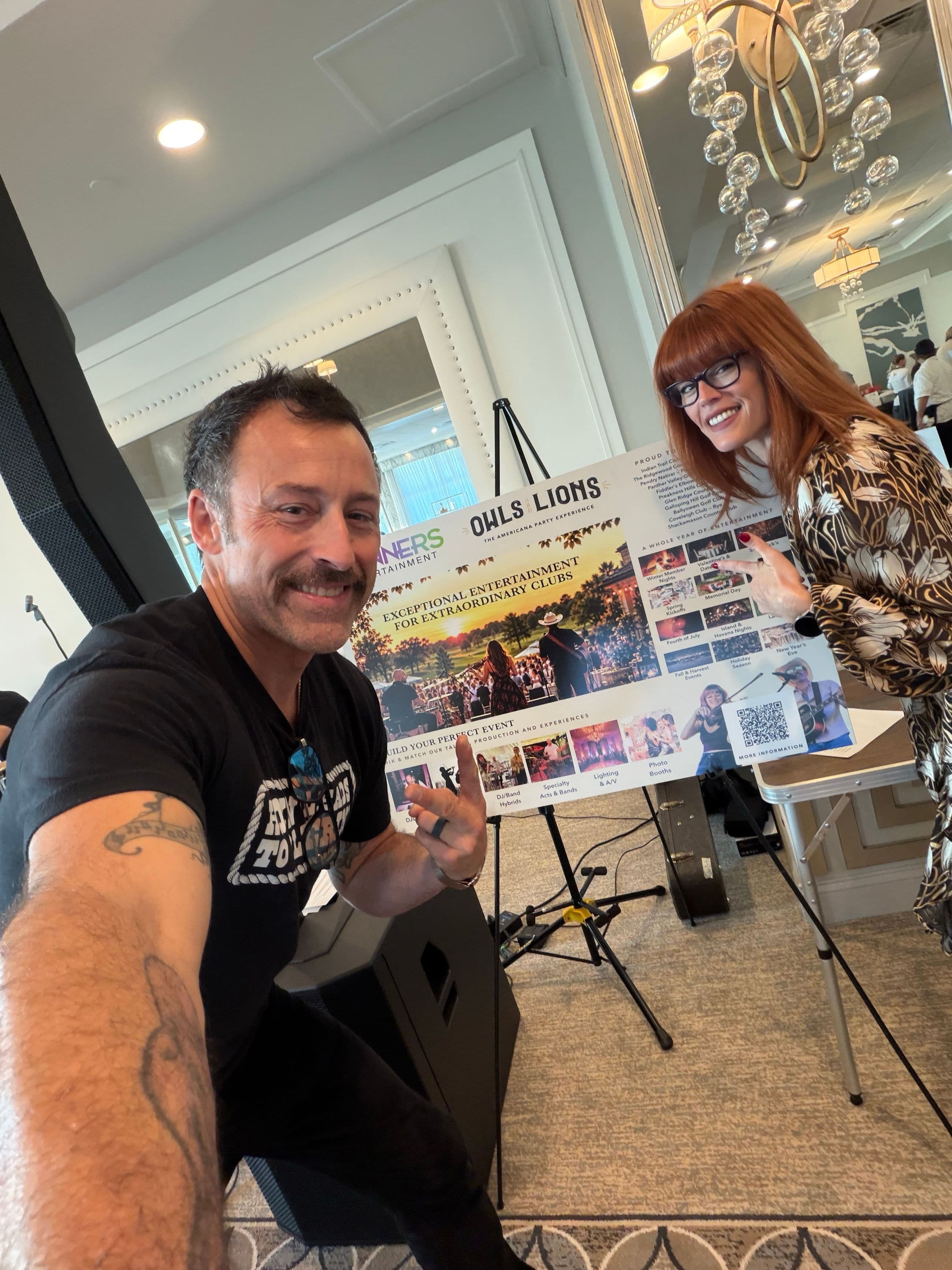 The Spinners Entertainment duo at a country club showcase, posing with the finished sign on an easel